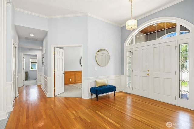 entryway featuring light wood-style floors, crown molding, and a healthy amount of sunlight