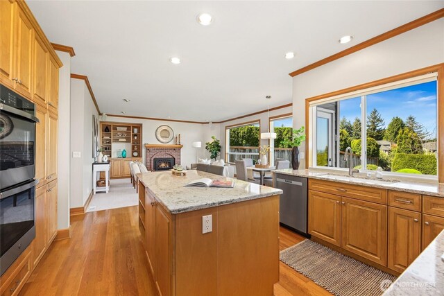 kitchen with crown molding, a sink, a kitchen island, stainless steel dishwasher, and multiple ovens