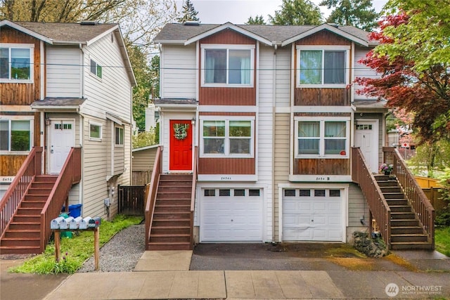 view of property featuring stairs, an attached garage, and driveway