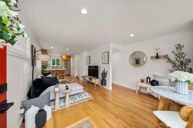 living room featuring recessed lighting, baseboards, and light wood-type flooring