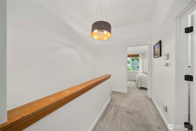 hall with baseboards, an upstairs landing, and light carpet