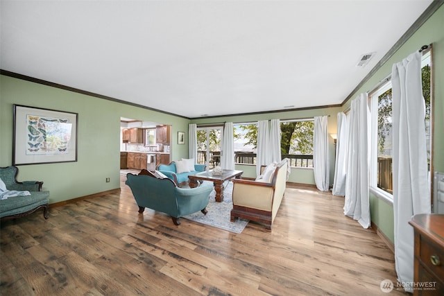 living area with baseboards, ornamental molding, wood finished floors, and visible vents