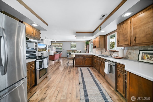 kitchen with visible vents, a peninsula, under cabinet range hood, a sink, and appliances with stainless steel finishes