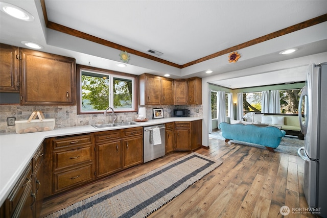 kitchen featuring appliances with stainless steel finishes, a sink, recessed lighting, backsplash, and hardwood / wood-style flooring