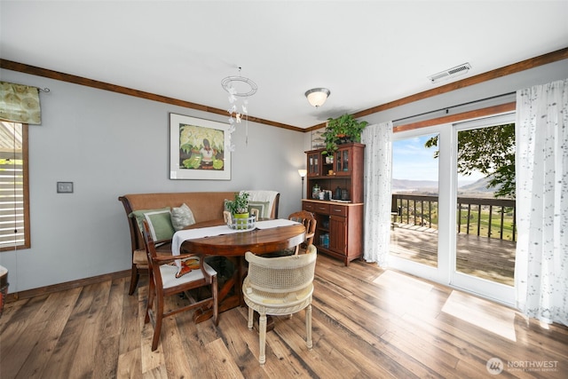 dining space featuring visible vents, light wood finished floors, crown molding, and baseboards