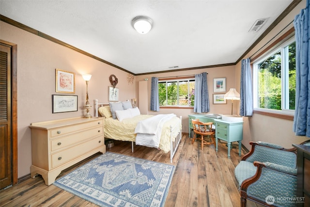 bedroom with visible vents, ornamental molding, and light wood-style flooring