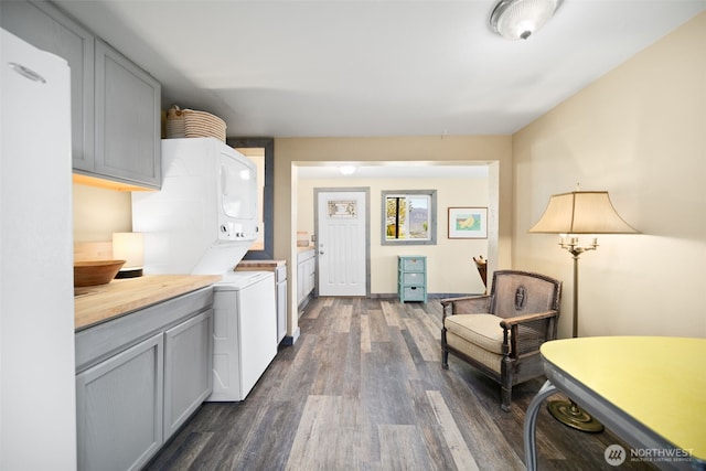 kitchen featuring dark wood-type flooring, stacked washing maching and dryer, and gray cabinetry