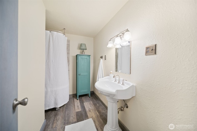full bath with a textured wall, a shower with shower curtain, and wood finished floors