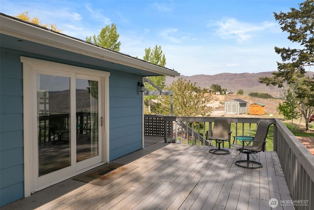 wooden terrace with an outbuilding, a mountain view, and a shed