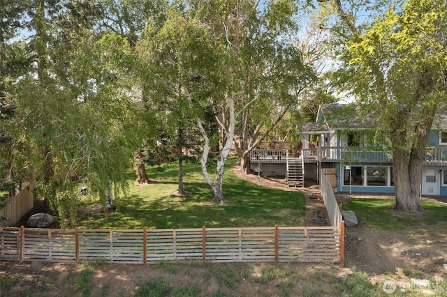 view of yard featuring a deck, a fenced backyard, and stairs