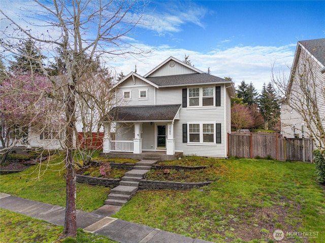 traditional home with a shingled roof, fence, a porch, and a front lawn
