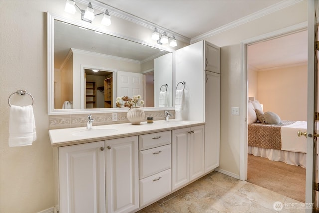 bathroom with ornamental molding, connected bathroom, double vanity, and a sink