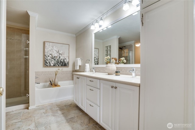 bathroom with ornamental molding, a shower stall, a garden tub, and a sink