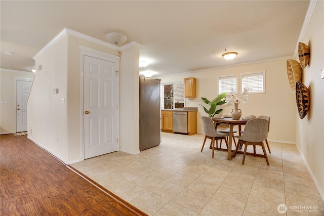 kitchen with ornamental molding, appliances with stainless steel finishes, and baseboards