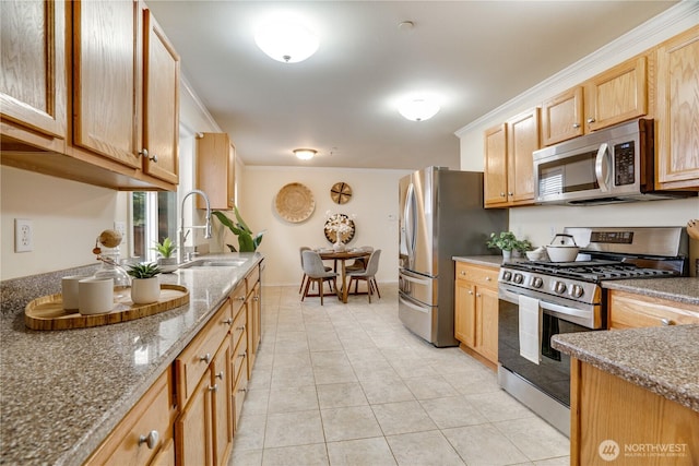 kitchen featuring a sink, appliances with stainless steel finishes, light brown cabinetry, light tile patterned flooring, and stone counters