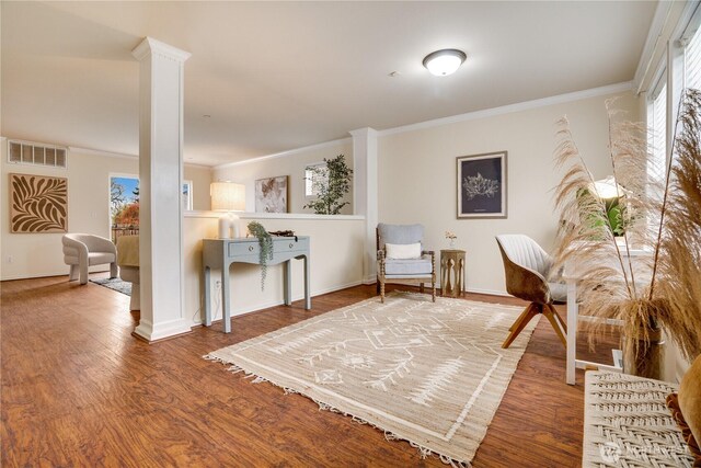 sitting room with ornate columns, visible vents, wood finished floors, and crown molding