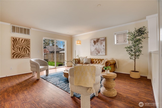 living room with ornamental molding, visible vents, wood finished floors, and baseboards