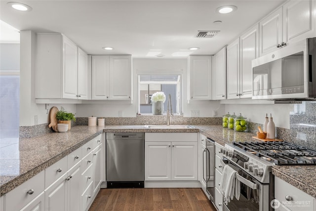 kitchen featuring tile counters, appliances with stainless steel finishes, white cabinetry, and a sink