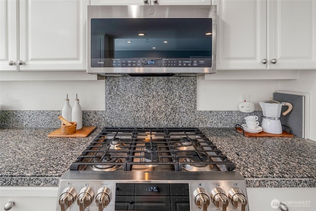 kitchen with decorative backsplash, white cabinets, dark countertops, and stainless steel appliances