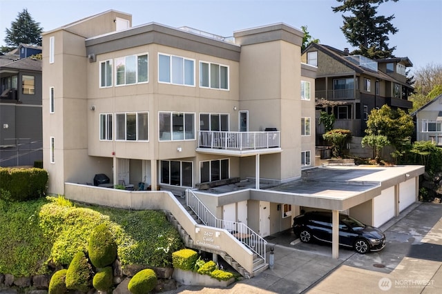 view of building exterior with a garage, stairs, a carport, and driveway