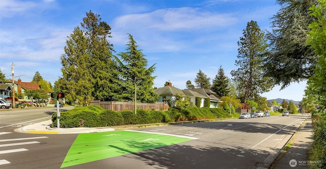 view of road with a residential view, sidewalks, curbs, and street lighting