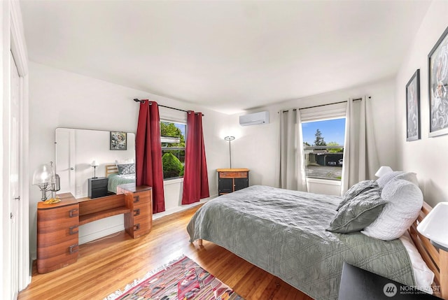 bedroom with a wall mounted air conditioner and wood finished floors