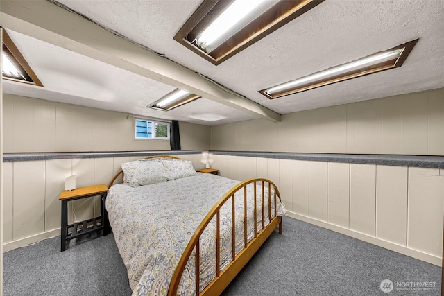 bedroom with carpet floors, a textured ceiling, and a decorative wall