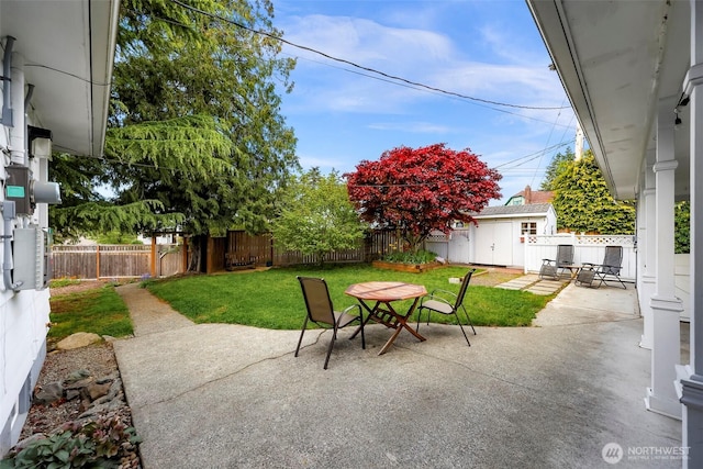 view of patio / terrace featuring an outbuilding, outdoor dining space, a fenced backyard, and a shed