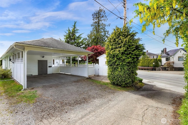 view of side of home with fence, a carport, and aphalt driveway