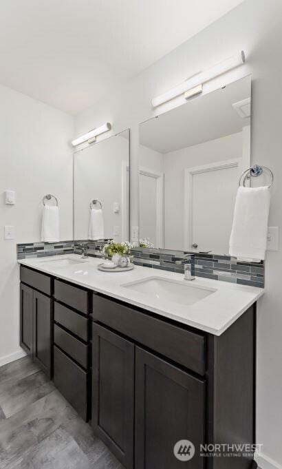 full bathroom featuring a sink, baseboards, and double vanity