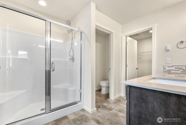 bathroom with vanity, baseboards, toilet, and a shower stall