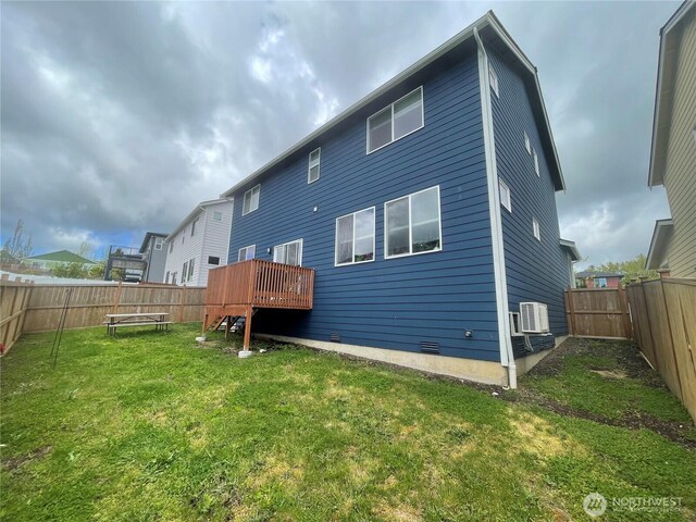 rear view of property with a fenced backyard, a wooden deck, and a yard