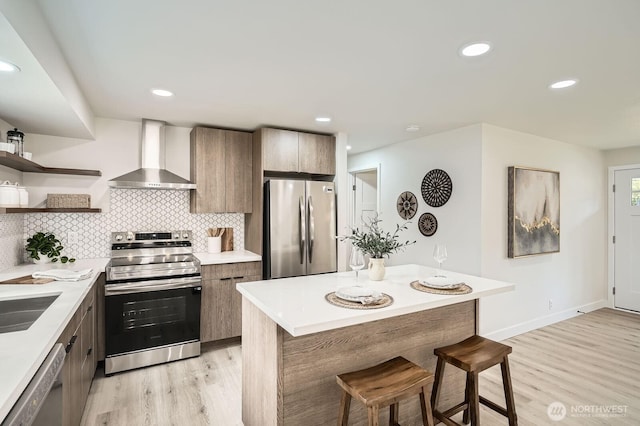 2613 Pike St SE, Auburn, WA 98002 - kitchen featuring stainless steel appliances, wall chimney range hood, light wood-style flooring, a breakfast bar area, and modern cabinets