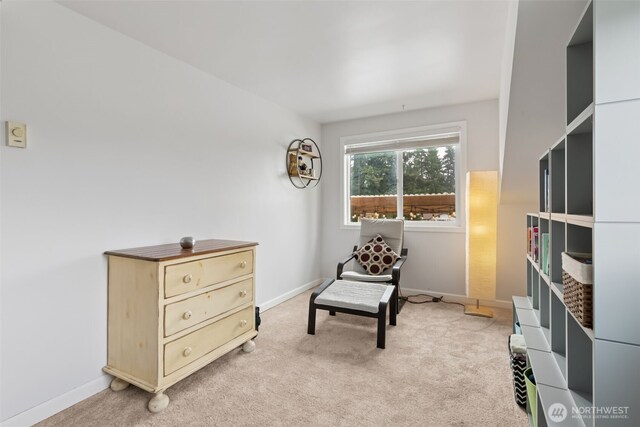 living area featuring light colored carpet and baseboards