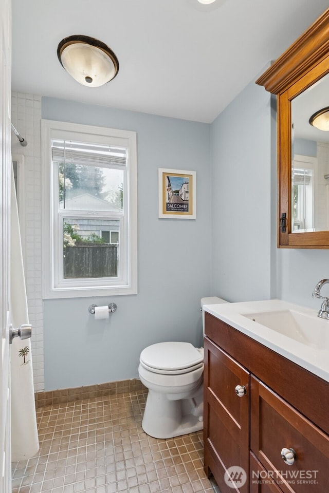 bathroom featuring toilet, a shower with shower curtain, tile patterned flooring, vanity, and baseboards