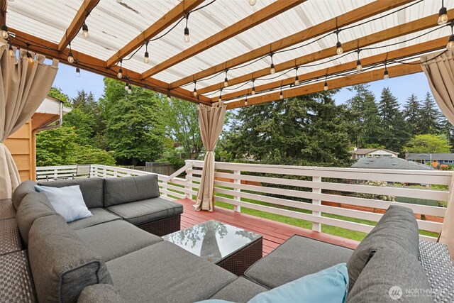 deck featuring an outdoor hangout area, view of scattered trees, and fence