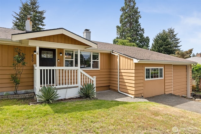 view of front of house with a chimney, a front yard, and a shingled roof
