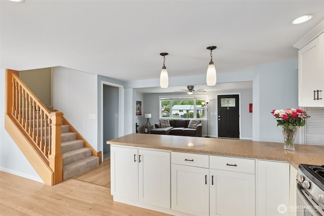 kitchen with ceiling fan, hanging light fixtures, open floor plan, light wood-style flooring, and white cabinetry