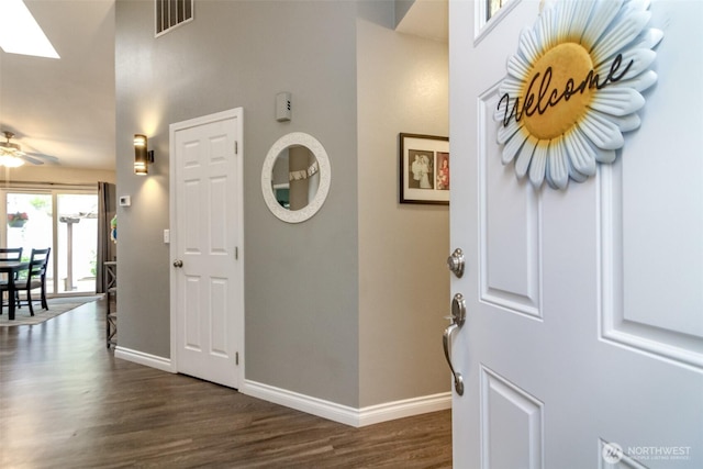 foyer with visible vents, a ceiling fan, dark wood finished floors, and baseboards