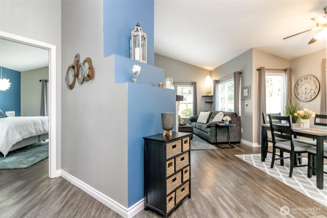 interior space featuring baseboards, a chandelier, wood finished floors, and vaulted ceiling