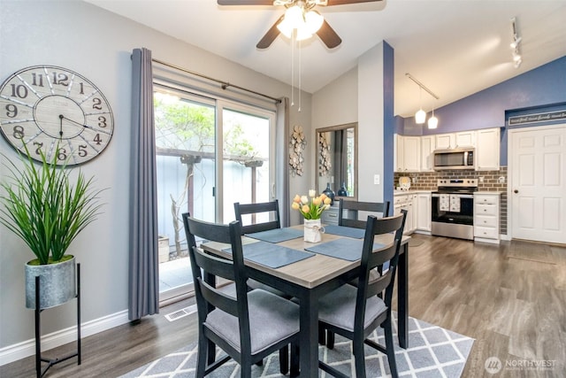 dining area featuring a ceiling fan, baseboards, lofted ceiling, visible vents, and dark wood-style floors