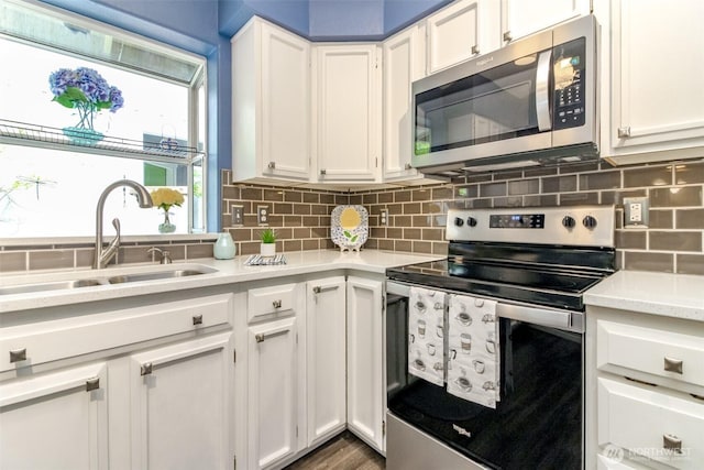 kitchen featuring a sink, light countertops, stainless steel appliances, white cabinetry, and backsplash