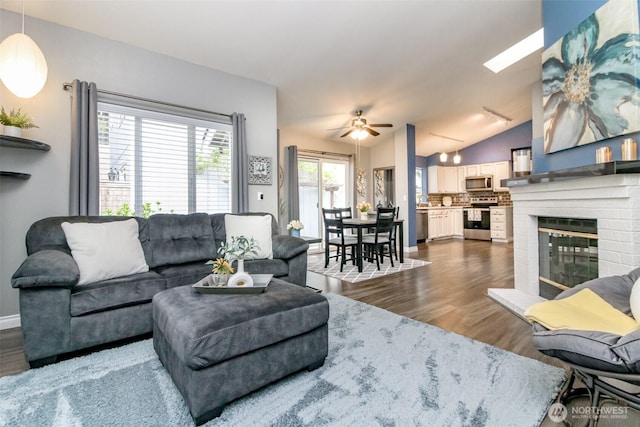 living room with a ceiling fan, dark wood finished floors, a brick fireplace, and lofted ceiling