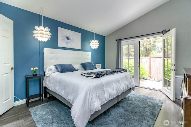 bedroom featuring access to outside, baseboards, vaulted ceiling, and wood finished floors