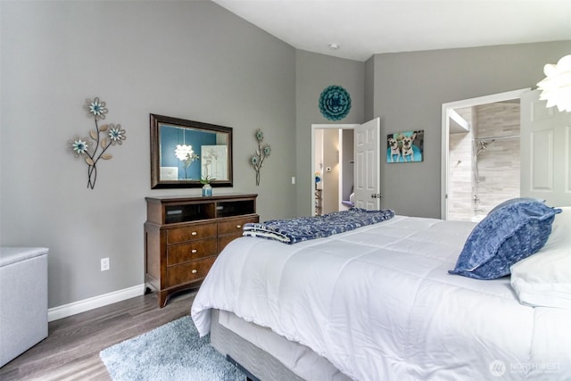 bedroom featuring baseboards, ensuite bath, wood finished floors, and lofted ceiling