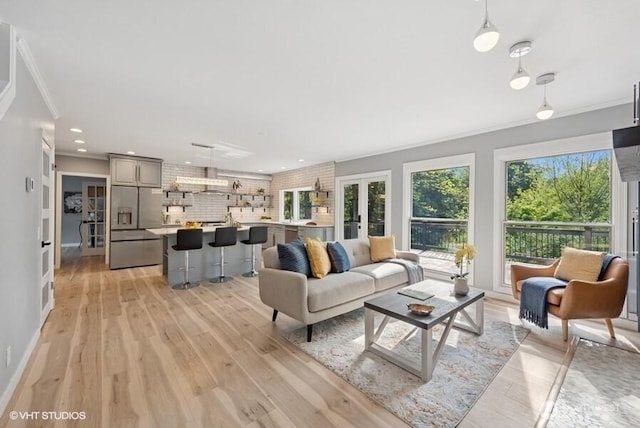 living area featuring french doors, crown molding, light wood-type flooring, baseboards, and recessed lighting