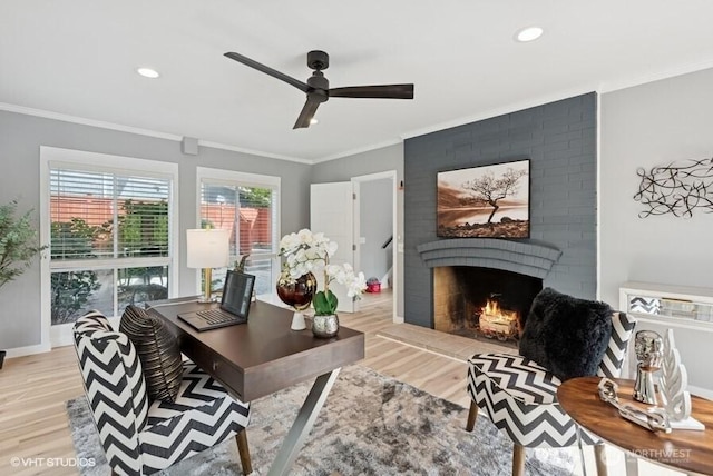 office featuring a ceiling fan, light wood finished floors, a fireplace, and ornamental molding