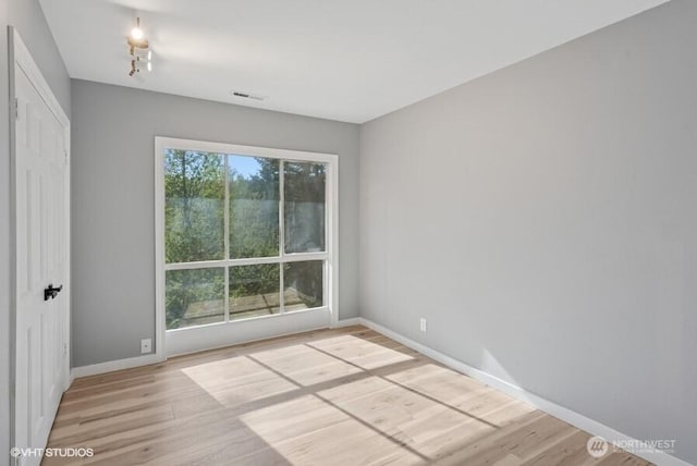 spare room with baseboards, visible vents, and wood finished floors