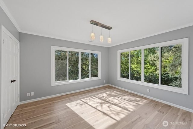 empty room with crown molding, baseboards, plenty of natural light, and light wood finished floors