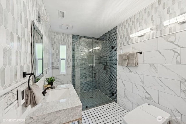 bathroom featuring visible vents, vanity, a shower stall, and tile walls